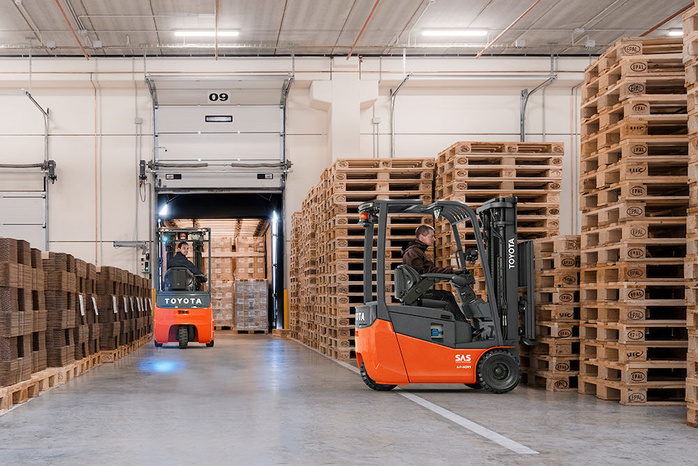Two orange Toyota Electric Forklifts in a warehouse